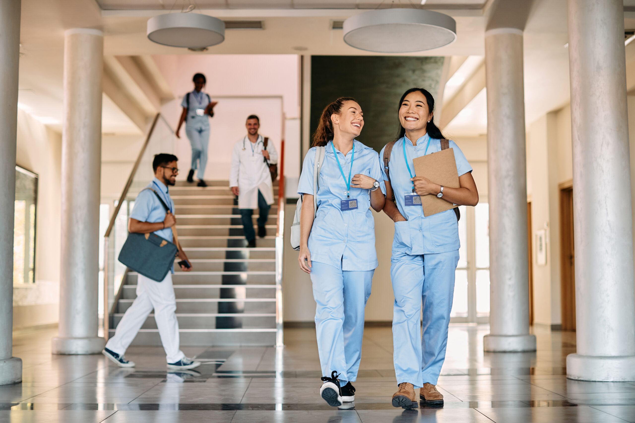 Happy female medical students walking through hallway at medical university.